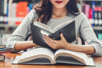 Gesundheitsmanagement-Studentin sitzt am Tisch und liest in einem Buch