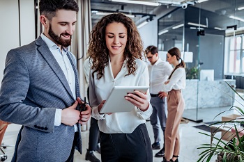 Business Kollegin und Kollege unterhalten sich freundlich im Büro