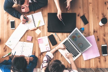 Studierende bearbeiten Statistiksaufgaben am Laptop und mit Berechnungen auf Papier.